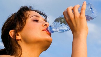 Young woman drinking water outdoors.
